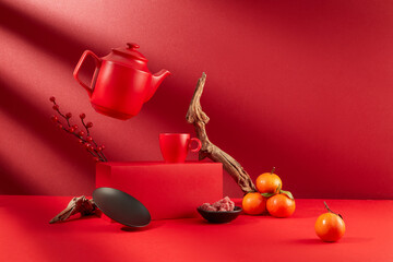 A pot of tea is suspended, a tea cup is placed on a red platform, a plate of jam, tangerines and decorations displayed on a red background. The atmosphere of Tet is brilliant.