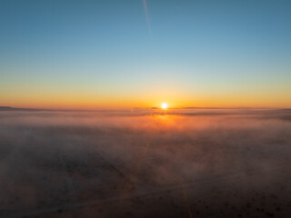 Fototapeta na wymiar Aerial Elegance with a Blanket of Fog Settled Across the Plains, Embracing the Distant Sunset