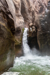 Naklejka premium A small waterfall on a tourist route in the Mujib River canyon in Wadi al-Mujib in Jordan