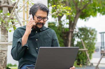 Middle aged businessman masterfully multitasks, managing a phone call while working on his laptop
