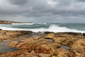 storm waves crashing on the rocky shores of Pembroke Beach in Malta