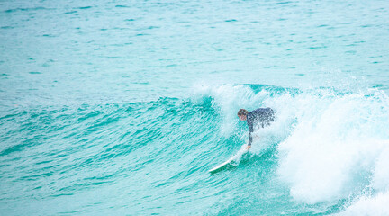 Naklejka premium Surfing on a water board. A professional surfer rides the waves in Bali, Indonesia. Male athlete catches waves in the ocean.