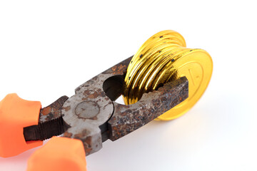 Rusty pliers hold the gold coin