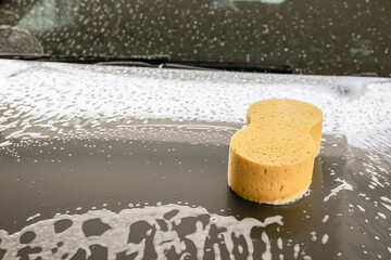car cleaning and washing with yellow sponge and foam soap