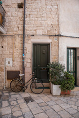 Fototapeta na wymiar Bike parked near green door of old stone house in Polignano a Mare old town
