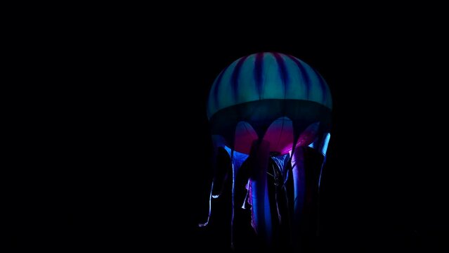 Blue jellyfish balloon illuminated at night during a parade