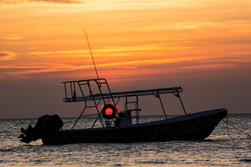 Boat silhouetted against a beautiful sunset in the middle of a tranquil sea