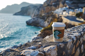 A Starbucks coffee cup on a rocky cliff overlooking the ocean.