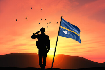 Silhouette of a soldier with the Nauru flag stands against the background of a sunset or sunrise....