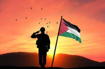 Silhouette of a soldier with the Palestine flag stands against the background of a sunset or sunrise. Concept of national holidays. Commemoration Day.