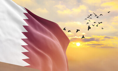 Waving flag of Qatar against the background of a sunset or sunrise. Qatar flag for Independence Day. The symbol of the state on wavy fabric. - obrazy, fototapety, plakaty