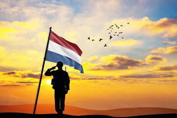 Silhouette of a soldier with the Netherlands flag stands against the background of a sunset or sunrise. Concept of national holidays. Commemoration Day.