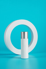 Plastic white tube for cream or lotion. Skin care or sunscreen cosmetic with stylish props on blue background 