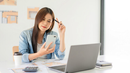 Construction design concept, Female architect using smartphone during thoughtful about house plan