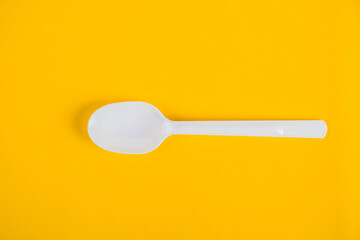 White plastic spoon on yellow background
