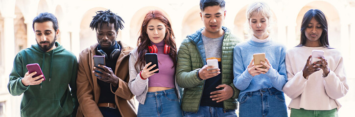 Multicultural group of university students focused on smartphones, embracing mobile technology and connectivity.