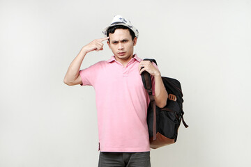 Asian man backpacker ponting finger on his head gesture. with confused, thinking, stressful expression. digital nomad and travelling concept. on isolated background