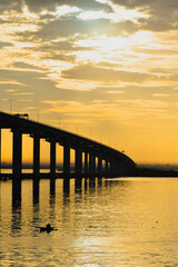 Fototapeta na wymiar golden sunrise over the bridge with fishing boat