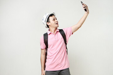 Asian man backpacker taking selfie photos with mobile phone. digital nomad and travelling concept. on isolated background