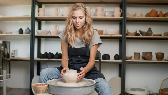 Pottery workshop, pretty woman ceramist at work, potter makes a pitcher out of clay, handicraft, young woman teaches a master class online.