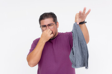 A disgusted middle aged man covers his nose while holding a stinky and soiled pair of briefs with his hand. Isolated on a white background. - obrazy, fototapety, plakaty