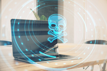 Close up of laptop on wooden desk with abstract round skull interface on blurry background. Hacking...