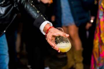 Detail of a hand holding a glass of cider at an event in a cider house, an alcoholic drink from the...