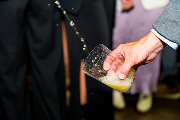 Hand holding a glass of cider at an event in a cider house, an alcoholic drink from the Basque...