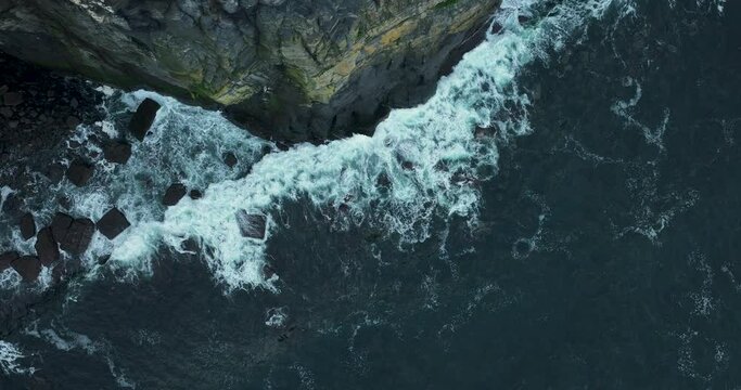  White waves crash against high rocks in 4k