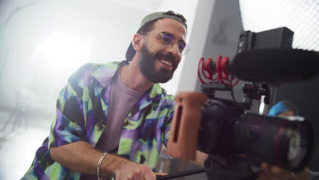 Portrait of Young Videographer Working on Set, Giving Instructions to the Filmed Model. Male Cinematographer Operating an Advanced Digital Camera To Capture High Quality Footage. Slow Motion