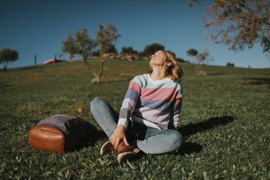 Woman sitting with backpack and relaxing on grass