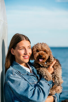 Smiling woman with poodle dog on sunny day