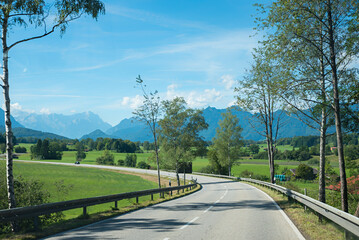 country road towards Ohlstadt, with view to Zugspitze mountain, trees beside
