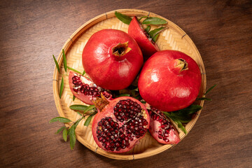 Fototapeta na wymiar Pomegranate on wooden basket on wooden background, Pomegranate with slices on wooden Background.