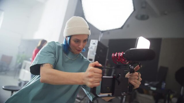 Portrait of Cinematographer Working On a Filming Set, Using Mobile Smartphone Rig to Shoot High-Quality Footage for Cinematic Project. Female Creative Artist Operating Modern Cinema Equipment