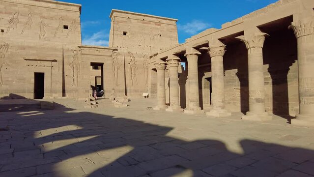 Aswan, Egypt: Exterior footage of the Philae Temple on the Nile river in Upper Egypt in Africa. Shot with a tilt up motion without people with the shadow of columns. 