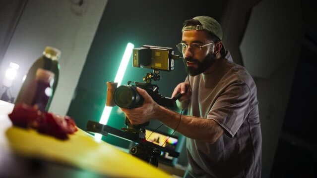 Slow Motion Shot of Male Cinematographer Working On a Filming Set, Using Digital Camera to Shoot Table top Footage for Cinematic Project. Creative Man Operating a Camera To Film Macro Shots