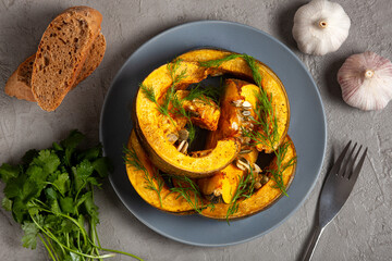 Pumpkin baked in the oven, toast, herbs and onions on a gray background, top vew. Concept of healthy eating or vegetarian food. The concept of Thanksgiving. 