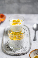 Chia pudding with passion fruit puree and yogurt in a glass on a grey background. Healthy vegetarian food. Tasty breakfast idea. Parfait with tropical fruit.