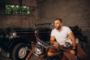 Fototapeta na wymiar A man sits on a retro motorcycle in his garage