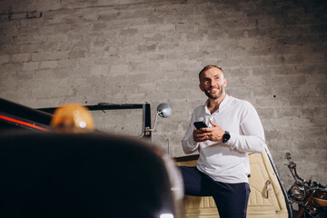 portrait of a man near a retro car in a white shirt in a garage