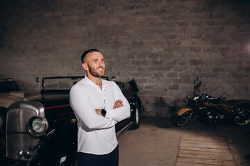 portrait of a man near a retro car in a white shirt in a garage