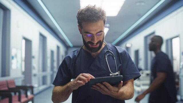 Tracking Shot of Latin Doctor Walking in Hospital Corridor, Using a Digital Tablet. Smiling Male Surgeon Checking Brain MRI Images Before Surgery, Revisiting his Notes, Greeting his Colleagues