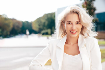 Young beautiful blond woman wearing nice trendy white suit jacket. Smiling model posing in the...