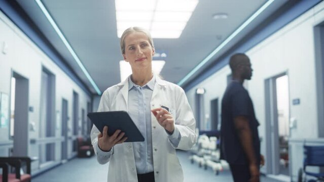 Tracking Shot of Doctor Walking in Hospital Corridor, Using a Digital Tablet. Smiling Female Surgeon Checking Brain MRI Images Before Surgery, Revisiting her Notes, Greeting her Colleagues