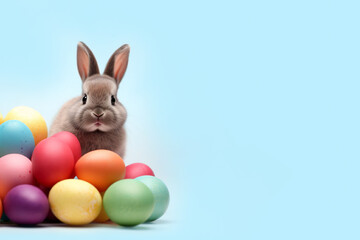 Fototapeta na wymiar The Easter bunny sits next to aEaster eggs, light blue background