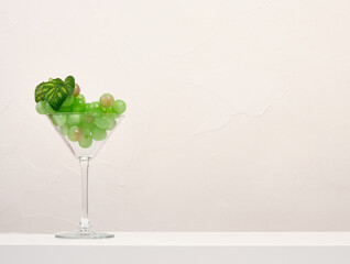 A wine glass with a ripe green bunch of grapes. Copy space for text. Alcohol party.