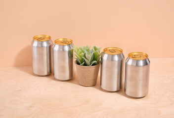 Aluminum cans with various cocktails standing in a row, a potted houseplant.