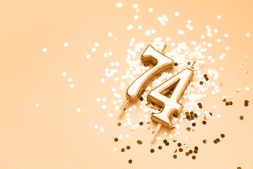 74 years celebration festive background made with golden candles in the form of number Seventy-four lying on sparkles. Universal holiday banner with copy space.