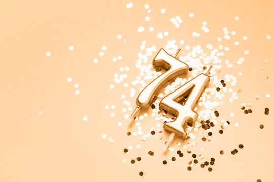 74 years celebration festive background made with golden candles in the form of number Seventy-four lying on sparkles. Universal holiday banner with copy space.